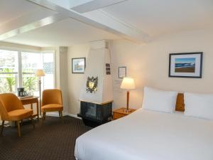 ein Hotelzimmer mit einem Bett, einem Schreibtisch und Stühlen in der Unterkunft Carmel Fireplace Inn in Carmel
