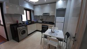 uma cozinha com mesa e cadeiras e uma cozinha com máquina de lavar roupa em magnifique appartement em Tânger