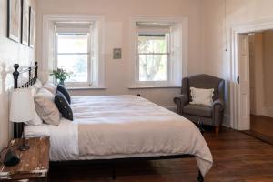 a bedroom with a bed and a chair and two windows at Surgeon's Cottage in Morpeth