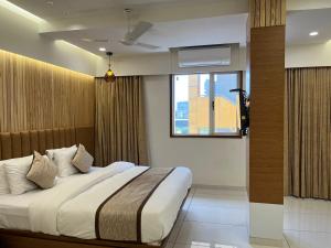 a bedroom with a large bed with a window at Tulsi Hotel in Surat