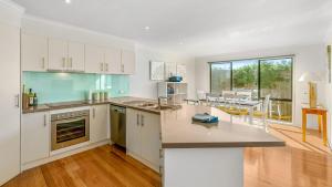 an open kitchen with white cabinets and a dining room at Island Holidayze in Cowes