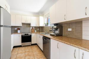 a white kitchen with white cabinets and appliances at Randwick l 3 Bedroom Apartment + Parking in Sydney