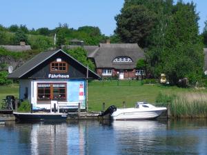 ein kleines Boot an einem Dock mit einem Haus angedockt in der Unterkunft Maisionette Wohnung im Hafenmeisterhaus Lauterbach in Lauterbach