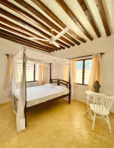 a bedroom with a canopy bed and a chair at Beautiful Mafriza Apartment in Lamu