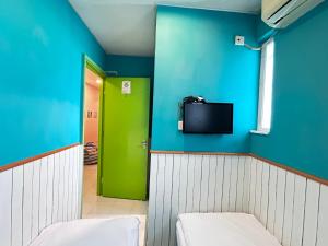 Habitación con puerta verde y TV en la pared. en 香港名都商务旅馆 self-check-in en Hong Kong