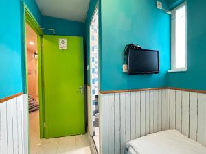 Zimmer mit grüner Tür und einem TV an der Wand in der Unterkunft 香港名都商务旅馆 self-check-in in Hongkong