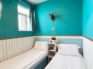 two beds in a room with a stag head on the wall at 香港名都商务旅馆 self-check-in in Hong Kong