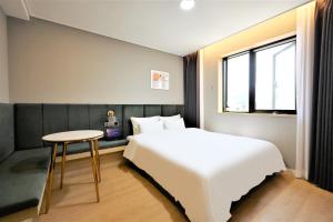 a bedroom with a bed and a table and a window at De Lamour Hotel in Tongyeong