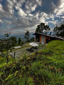 une maison assise au sommet d'une colline herbeuse dans l'établissement Deumadi Mountain Cottage, à Pokhara