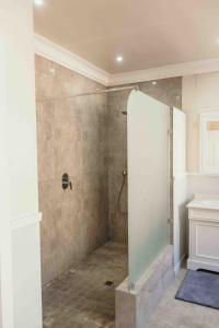 La salle de bains est pourvue d'une douche avec une porte en verre. dans l'établissement Milestone Farm House, à Balgowan