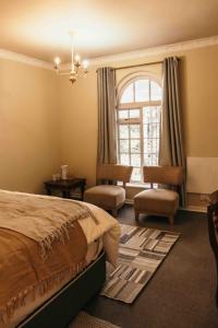 Balgowan的住宿－Milestone Farm House，一间卧室配有一张床、两把椅子和一个窗户