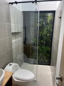 a bathroom with a toilet and a glass shower at A 1 minuto del aeropuerto MDE Medellín Rionegro - Casa Campestre Ficus in Rionegro