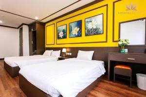 two beds in a hotel room with yellow walls at Lotus Village Hotel - 68 Hàng Bồ - by Bay Luxury in Hanoi