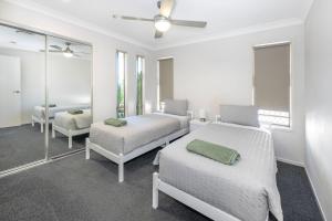 Habitación blanca con 2 camas y espejo. en Large house 7 mins from Airport en Brisbane