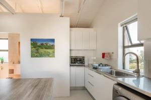 a kitchen with white cabinets and a sink at Vlei Cove in Cape Town