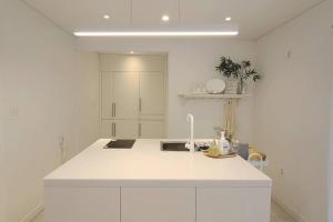 a white kitchen with a sink and a counter at Jeju Polaris Pension in Jeju