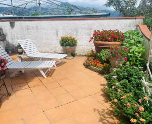 a patio with two chairs and flowers in pots at GIARDINO FIORITO in Camaiore