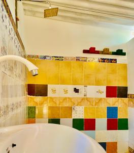 a bathroom with a tub and a colorful tiled wall at Reggae paradise hostel in Sigiriya