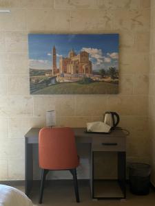 a desk with a red chair and a painting on a wall at Sea Holly Gozo in Nadur