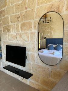 a bedroom with a stone wall with a mirror and a bed at Sea Holly Gozo in Nadur
