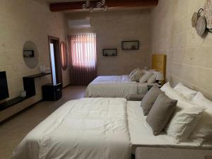 a hotel room with two beds and a couch at Sea Holly Gozo in Nadur