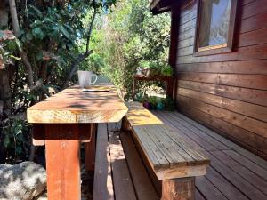 una mesa de madera y un banco en una terraza de madera en הבלוט - בקתה אינטימית בצל אלון en Abirim