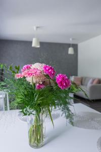 eine Vase voller rosa Blumen auf dem Tisch in der Unterkunft Arctic Holiday Apartments 1 in Rovaniemi