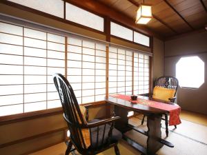 a room with a table and chairs and windows at Kisoji no Yado Iwaya in Kiso