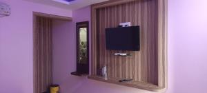 Habitación con espejo y TV en la pared. en Hotel Vedant en Port Blair