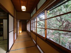 a corridor of a building with windows and trees at Kisoji no Yado Iwaya in Kiso
