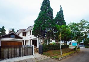une maison blanche avec deux arbres et une clôture dans l'établissement Andaru Graha Puspa For Family and Friends, à Bandung