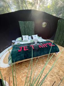 een bed met een groen dekbed en kussens bij Logement insolite "Bubble jungle" in Saint-Évarzec