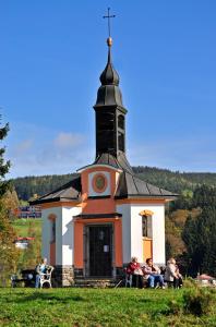 a group of people sitting in front of a church at Apartman Flora in Benecko