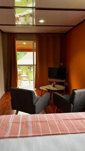 a bedroom with a bed and chairs and a table at Rupe Rupe Lodge in Uturoa