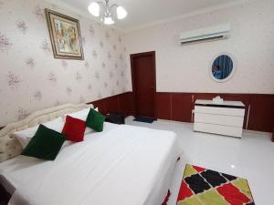 1 dormitorio con cama blanca y almohadas coloridas en Al Hedayet International Hotel, en Seeb