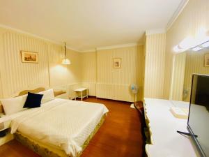 桃園市にあるLi Hua Hotelのベッドとテレビがあるホテルの部屋