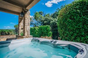 uma banheira de hidromassagem num pátio com uma sebe em Belle Villa au calme avec Superbe vue em Bagnols-sur-Cèze