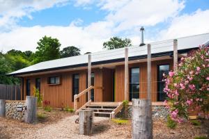 a wooden cabin with a porch and a fence at Wombat Hill Lodge in Daylesford