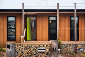 a wooden house with a stone wall in front of it at Wombat Hill Lodge in Daylesford +5 photos