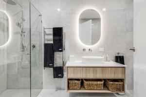 ein Bad mit einem Waschbecken und einer Dusche mit einem Spiegel in der Unterkunft Vale 194 - Newly built in McLaren Vale - 5 holiday homes with king size beds in McLaren Vale