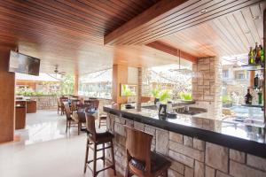 a restaurant with a bar with chairs and tables at Satriya Cottages in Kuta