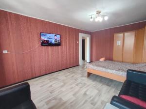 a bedroom with a bed and a tv on a wall at Galeto 22 Apartments in Semey