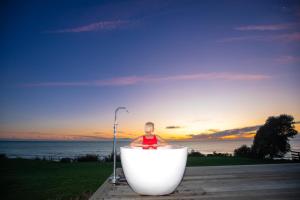 um homem sentado numa banheira com o oceano em MOKAU BEACH HOUSE em Mokau