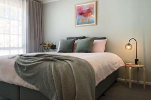 a bedroom with a bed with a blanket on it at Wood for the Trees in Hepburn Springs