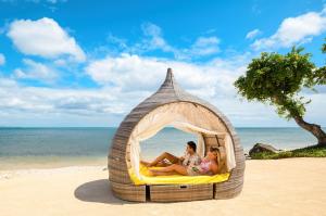 duas pessoas sentadas numa cápsula na praia em Le Jadis Beach Resort & Wellness - Managed by Banyan Tree Hotels & Resorts em Balaclava