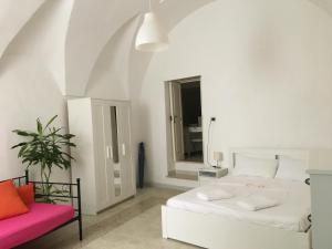 een witte slaapkamer met een bed en een stoel bij Medieval terraced house in Vieste Vecchia in Vieste