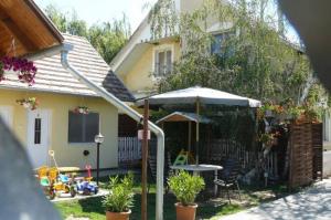 um pátio com um guarda-chuva e uma mesa em frente a uma casa em Cserke Gyöngye Apartman em Cserkeszőlő