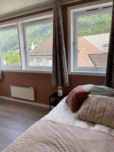 a bedroom with a bed and two large windows at Leilighet i Odda sentrum in Odda