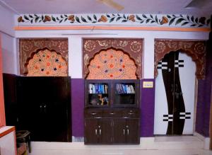 焦特布爾的住宿－Banasa Heritage Haveli，一间拥有紫色墙壁、电视和两个十字架的房间