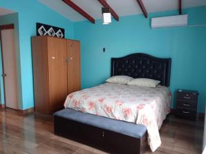 1 dormitorio con 1 cama y armario de madera en Cómoda casa con piscina, en Arica